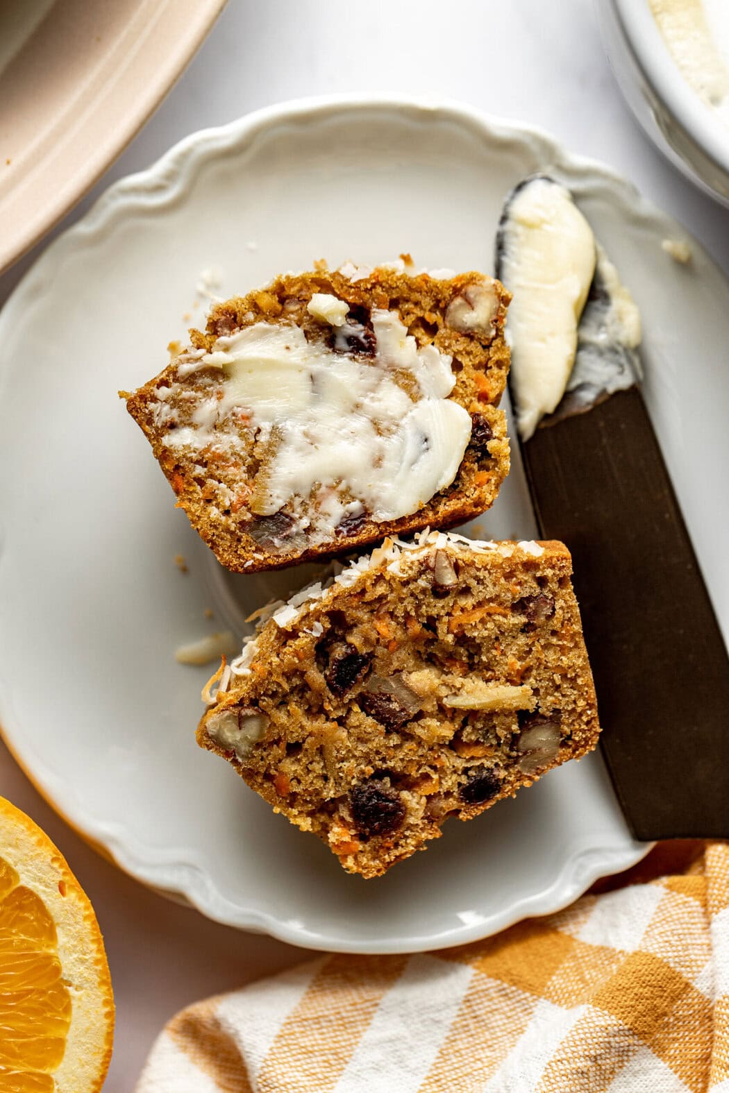 Overhead view of a Morning Glory Muffin cut in half and topped with butter. 