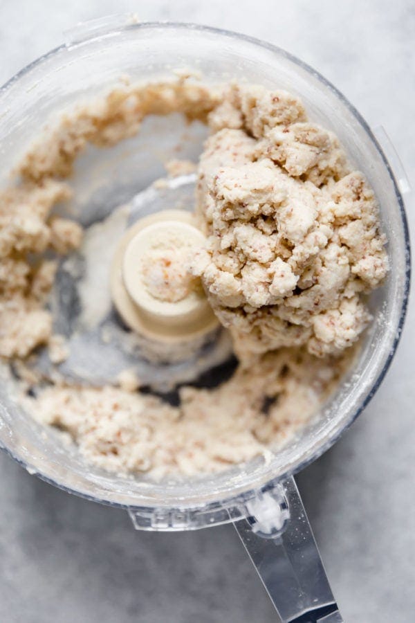 The bowl of a food processor contains the dough for the pastry crust used to top a Paleo Turkey Pot Pie. 