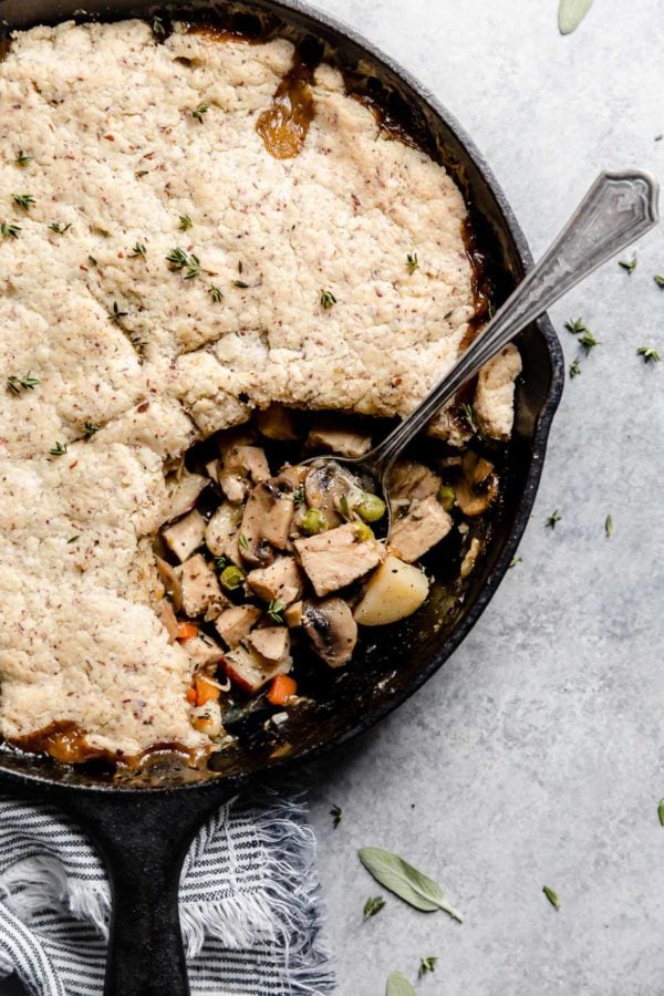 A spoon rests in a cast iron skillet where a servings of Paleo Turkey Pot Pie has been dished out. 