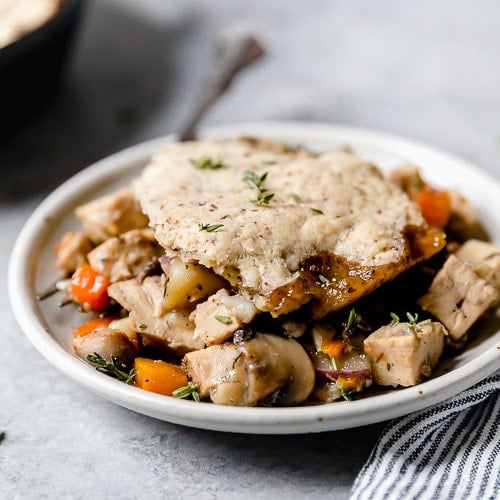 A plate of turkey and vegetables in a thyme-sage gravy is topped with a flaky grain-free pastry crust in this Paleo Turkey Pot Pie.