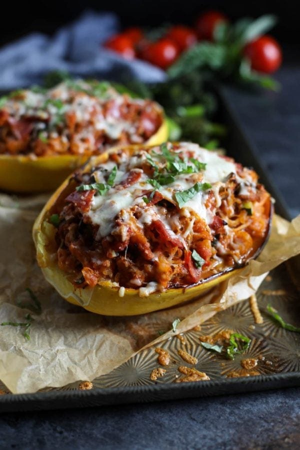 Two Pizza-Stuffed Spaghetti Squash halves on a baking sheet garnished with fresh basil.