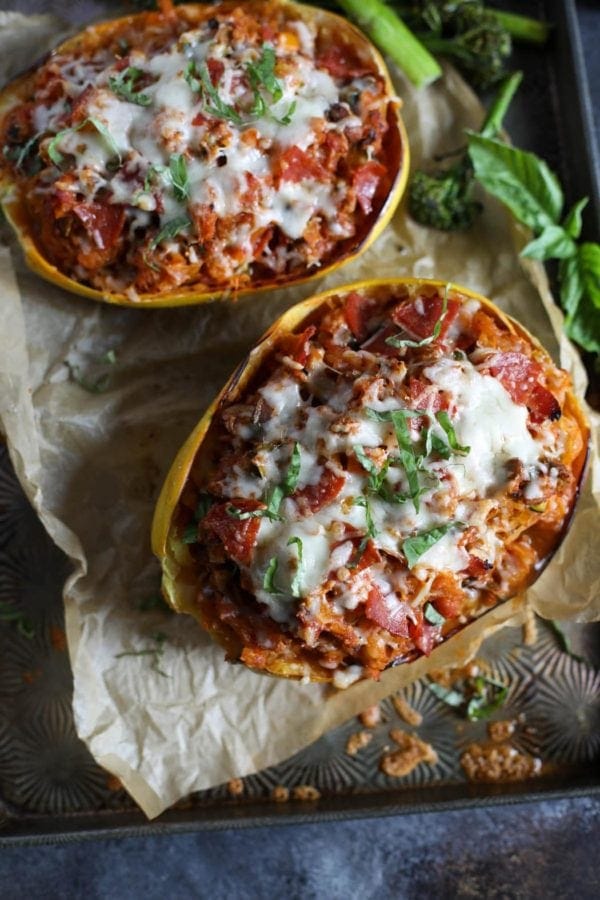 Overhead view of pizza-stuffed spaghetti squash featuring a saucy, veggie-packed filling and topped with melted cheese. 