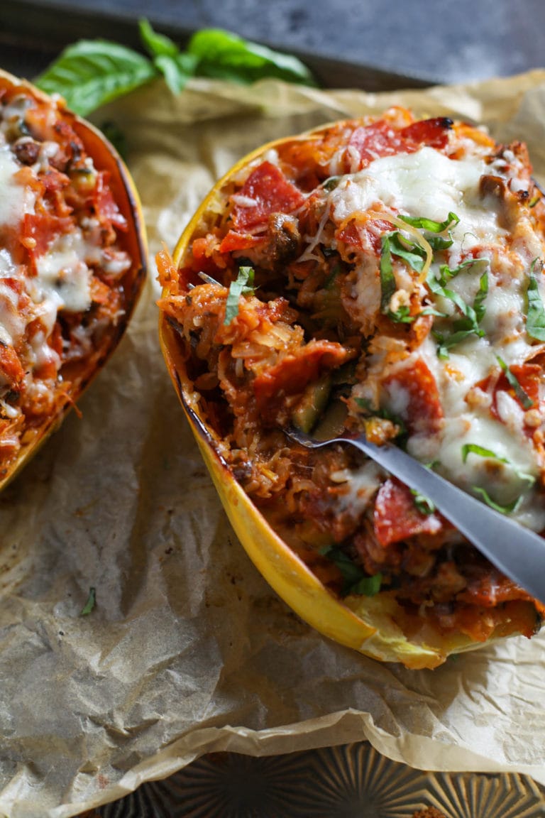 Two halves of pizza-stuffed spaghetti squash, a fork sticking out of one.