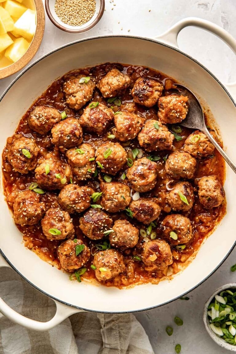 Overhead view of a skillet of sweet and sour meatballs sprinkled with sesame seeds.