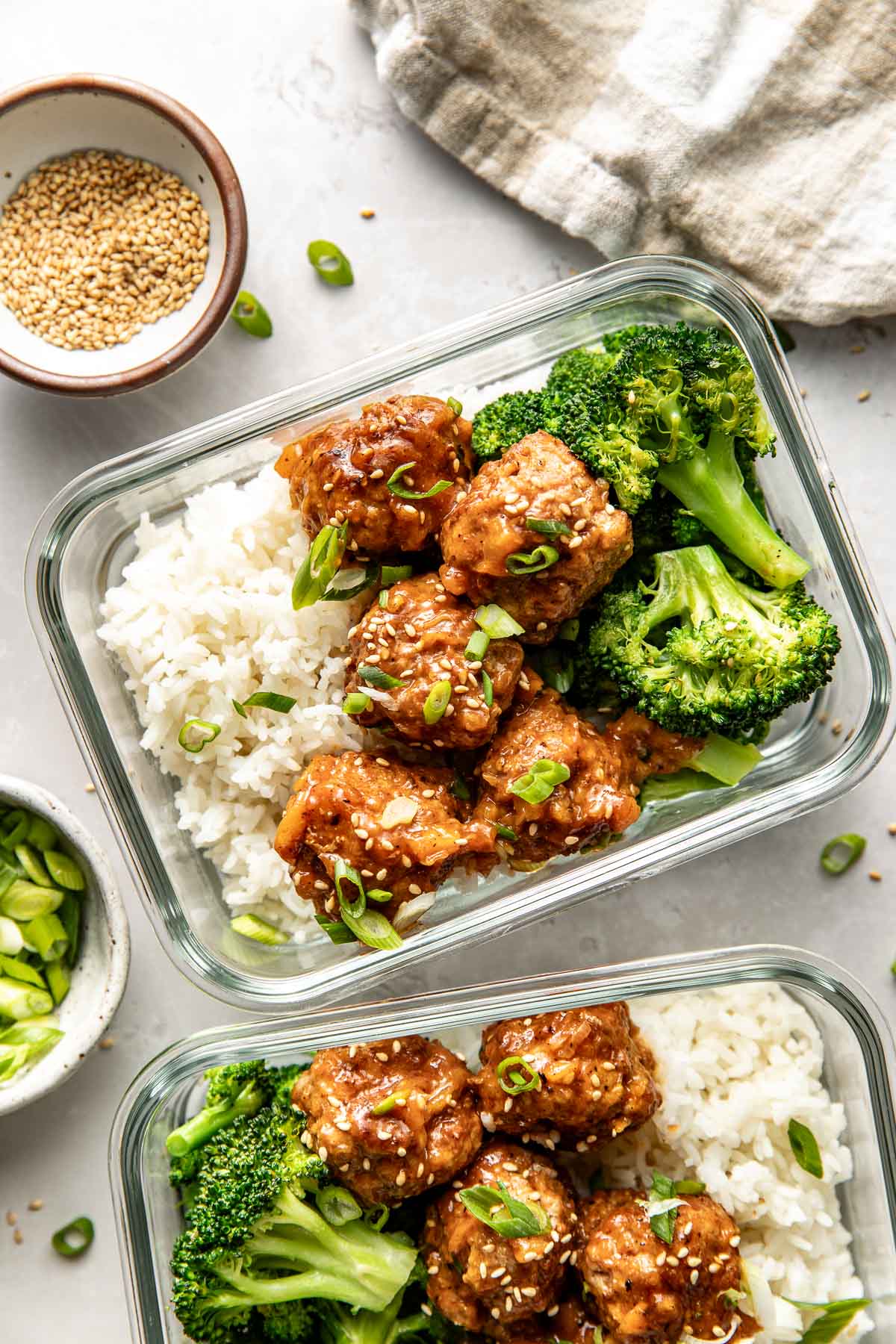Overhead view of two glass meal prep containers filled with white rice, broccoli, and sweet and sour meatballs.