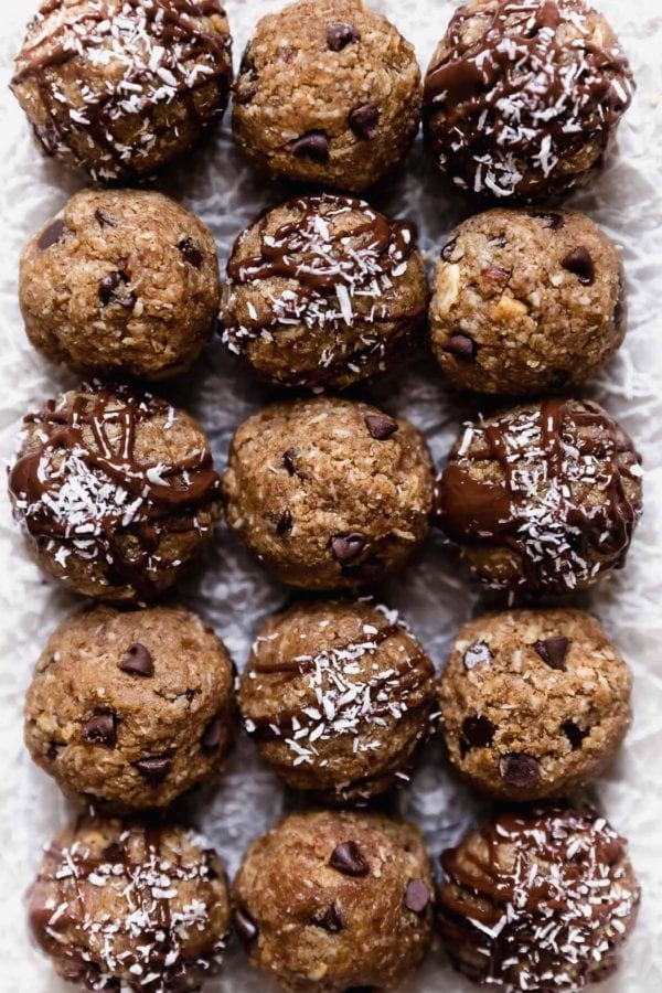 Rows of Almond Joy Protein Bites arranged side-by-side. Some are drizzled with melted chocolate and others are studded with mini chocolate chips.