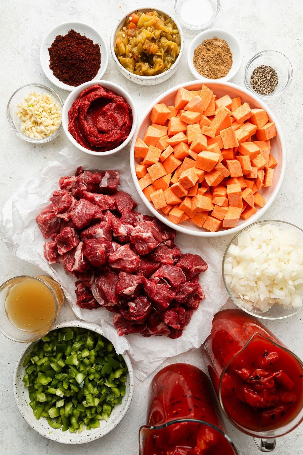 Overhead view of a variety of ingredients for Slow Cooker Chuck Roast Chili with Sweet Potatoes in different sized bowls.