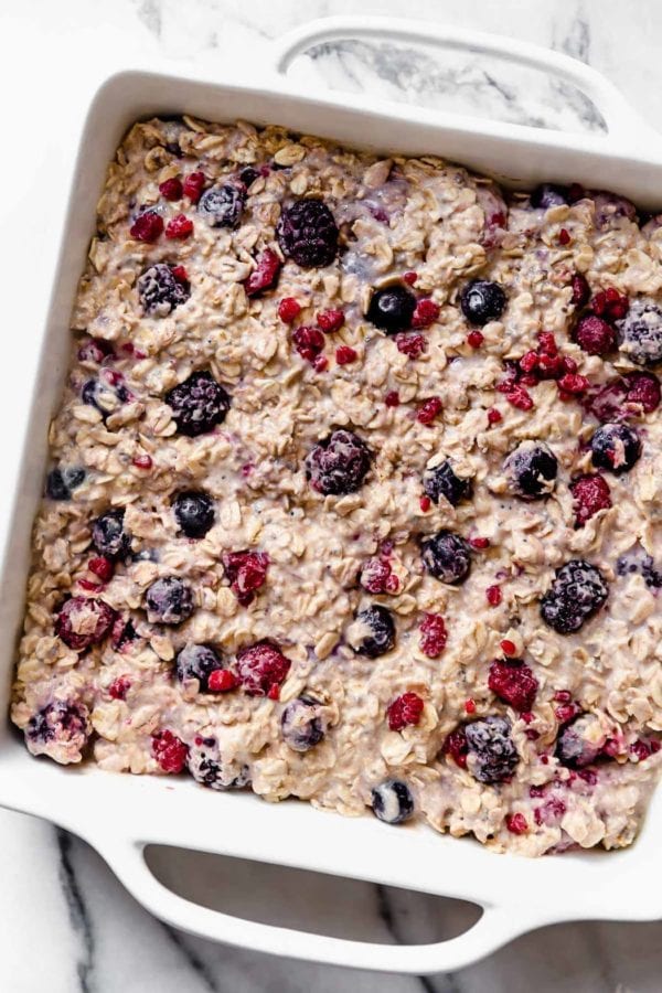 A white square dish is filled with a berry-studded oat mixture to make our Mixed Berry Baked Oatmeal.