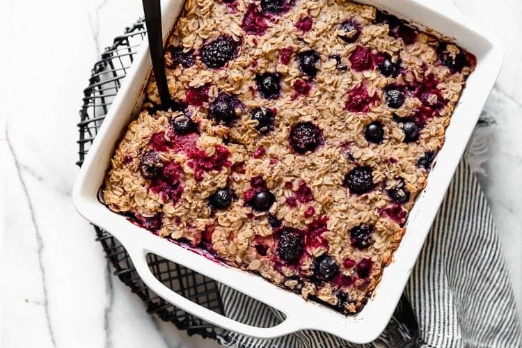 Overhead view mixed berry baked oatmeal in white baking dish topped with mixed berries