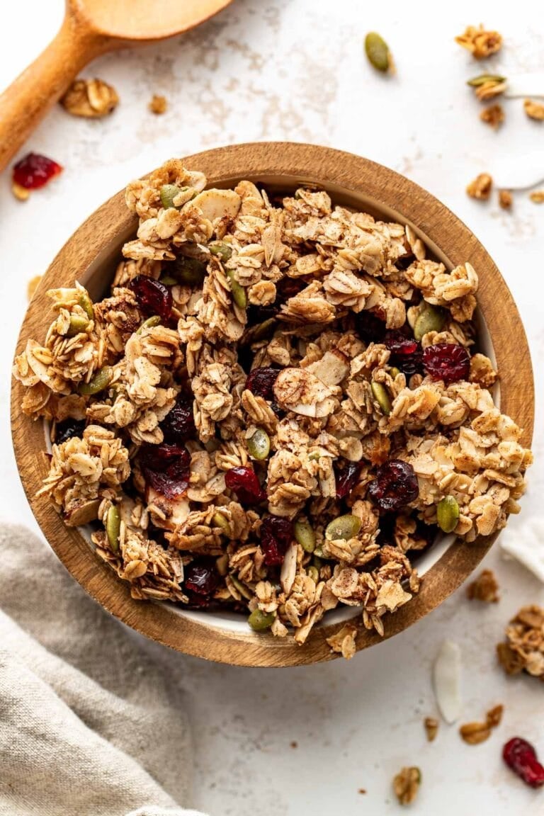 Overhead view of a bowl of homemade granola showing the crunchy texture and pieces of dried fruit throughout the pieces.