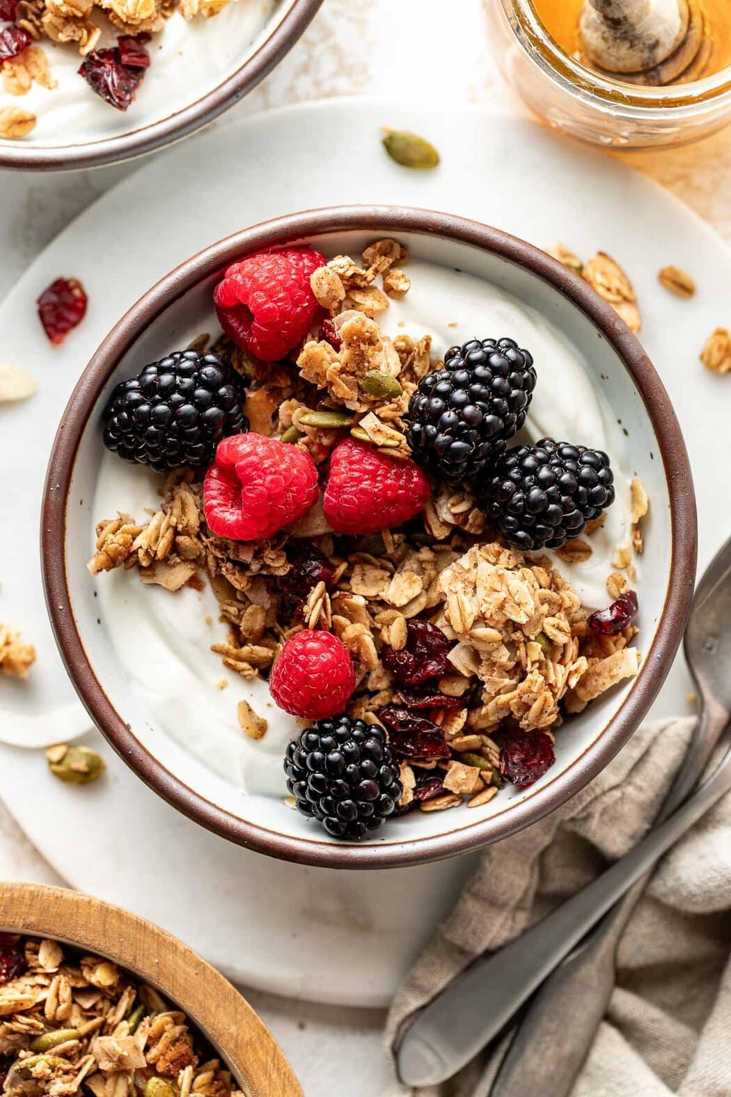 Overhead view of a small bowl of yogurt topped with Homemade Granola and fresh colorful berries. 