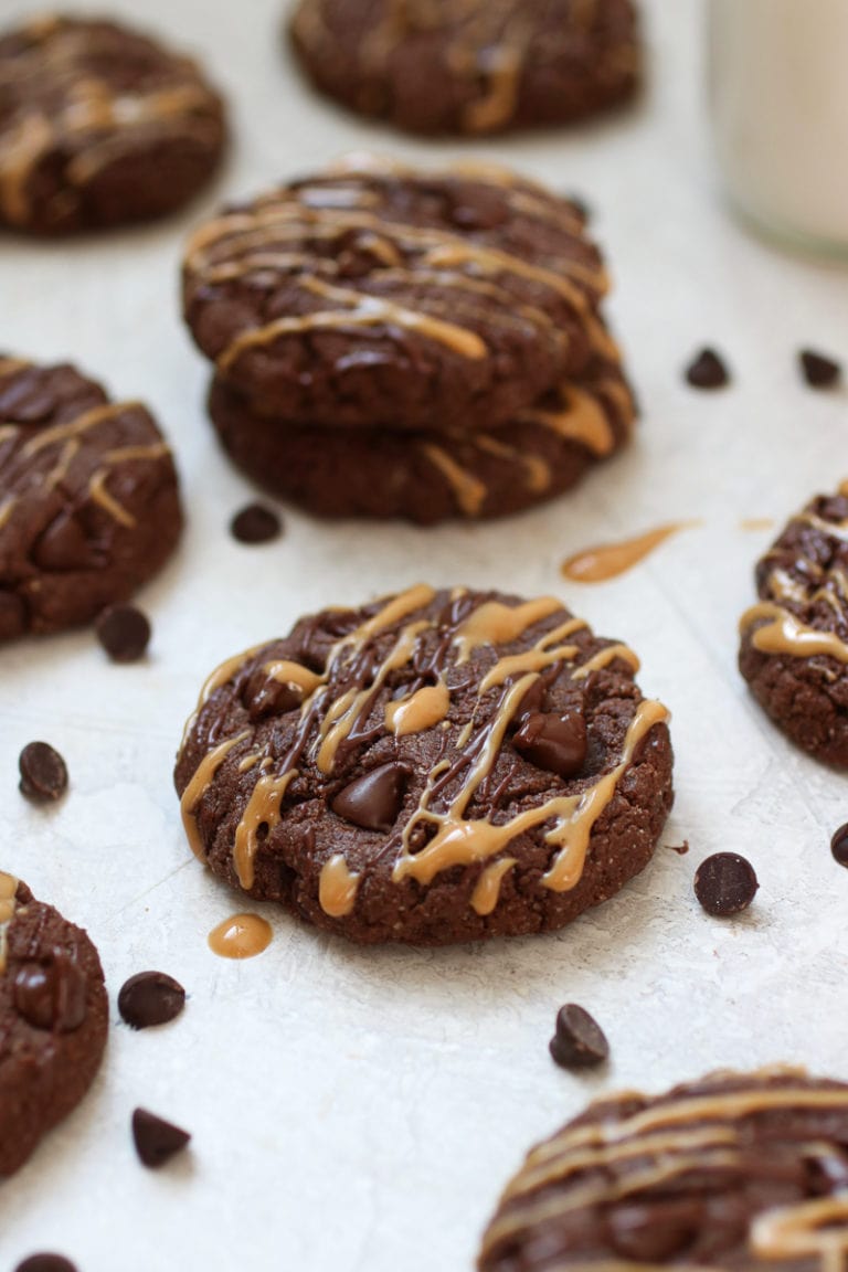 Close up view of chocolate peanut butter protein cookies drizzled with peanut butter and topped with chocolate chips. 