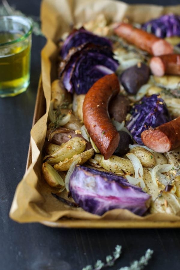 Close up of Sheet Pan Kielbasa, Cabbage and Potatoes with a lager in the background. 