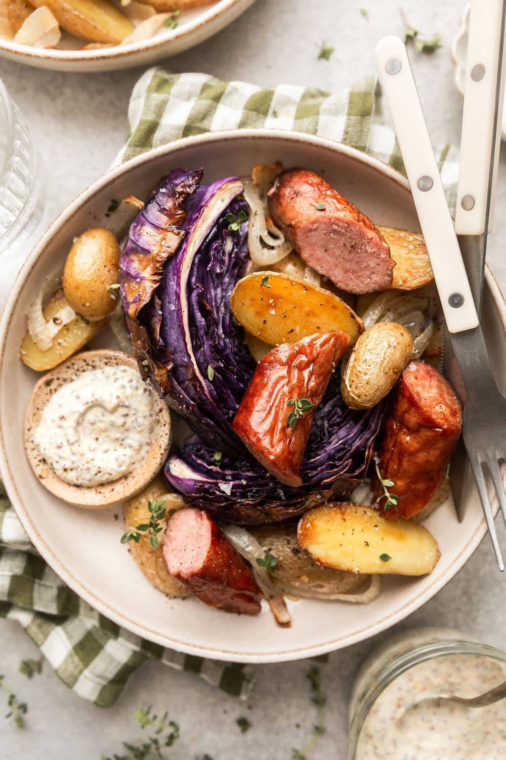 Overhead view of a plate filled with Kielbasa and Potatoes with red cabbage sprinkled with fresh herbs.