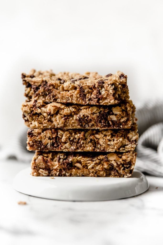 Four soft-baked granola bars stacked vertically on top of a white plate