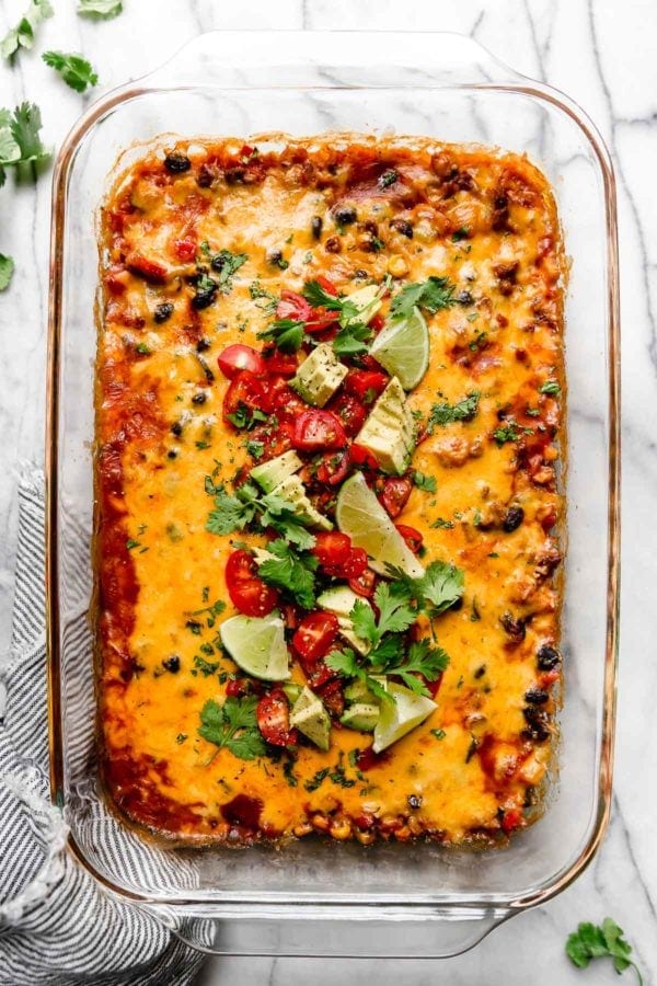 Overhead view entire casserole dish filled with healthy taco casserole, topped with diced tomatoes, avocado, and cilantro.