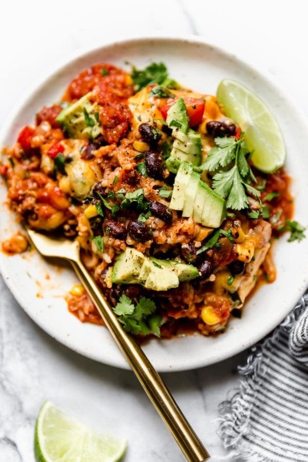 Serving of healthy taco casserole on white plate with gold fork