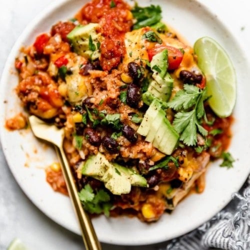 Serving of healthy taco casserole on white plate with gold fork.