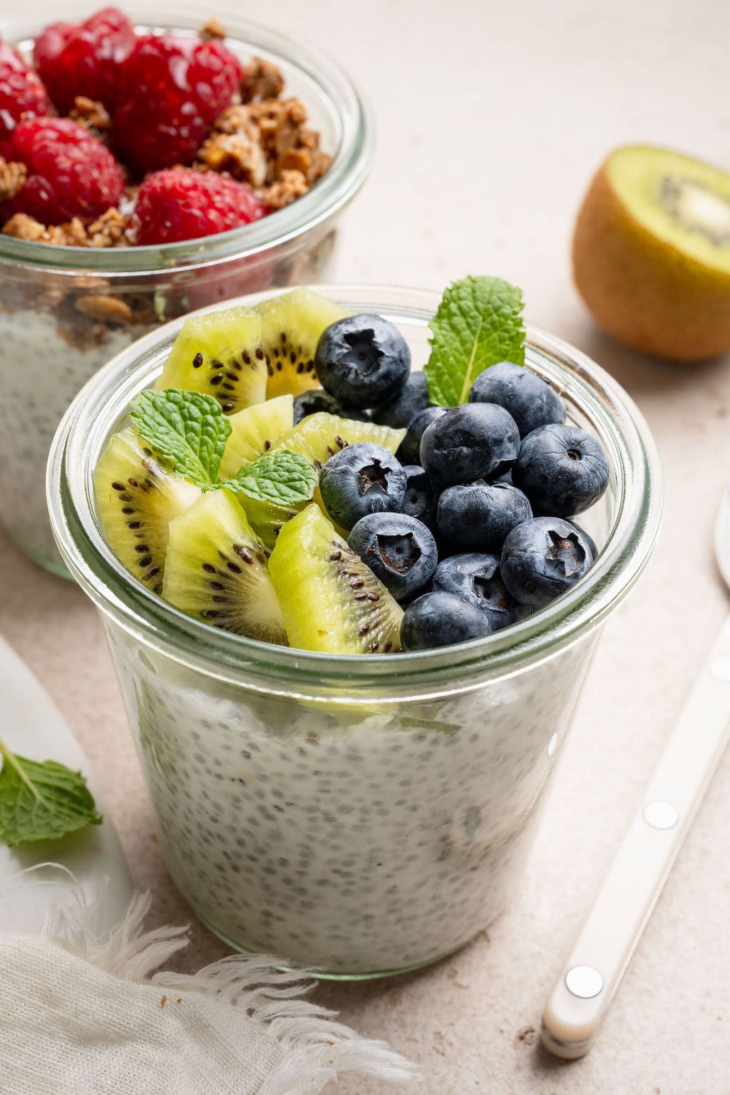 A jar of chia seed pudding topped with kiwi, blueberries, and mint.