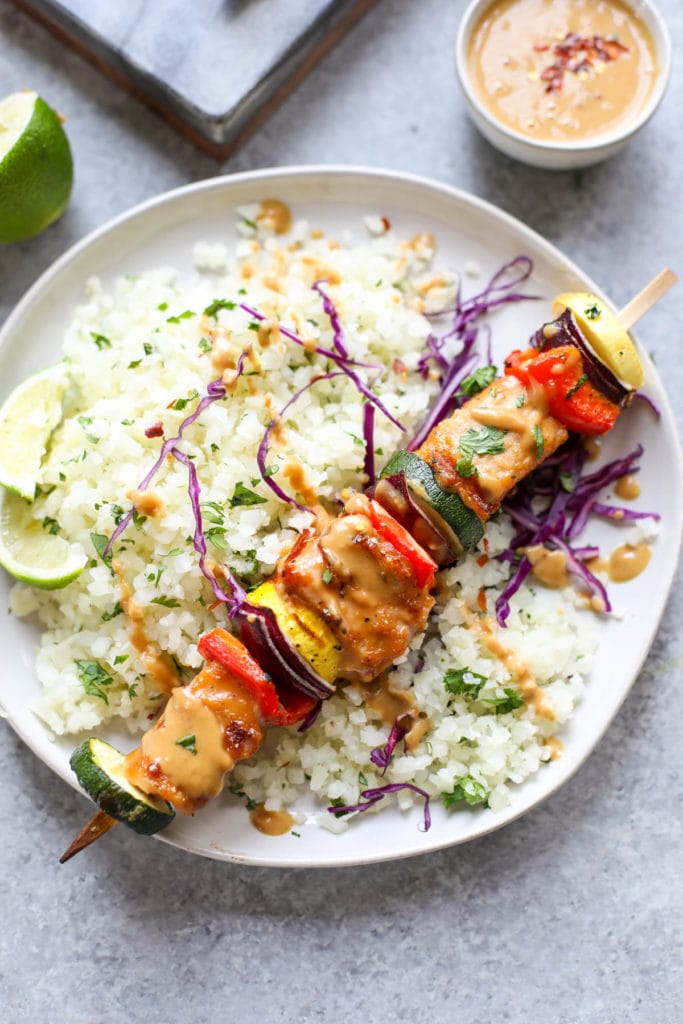 Overhead view of a plate of rice and Grilled Pork Kebabs with Peanut Sauce