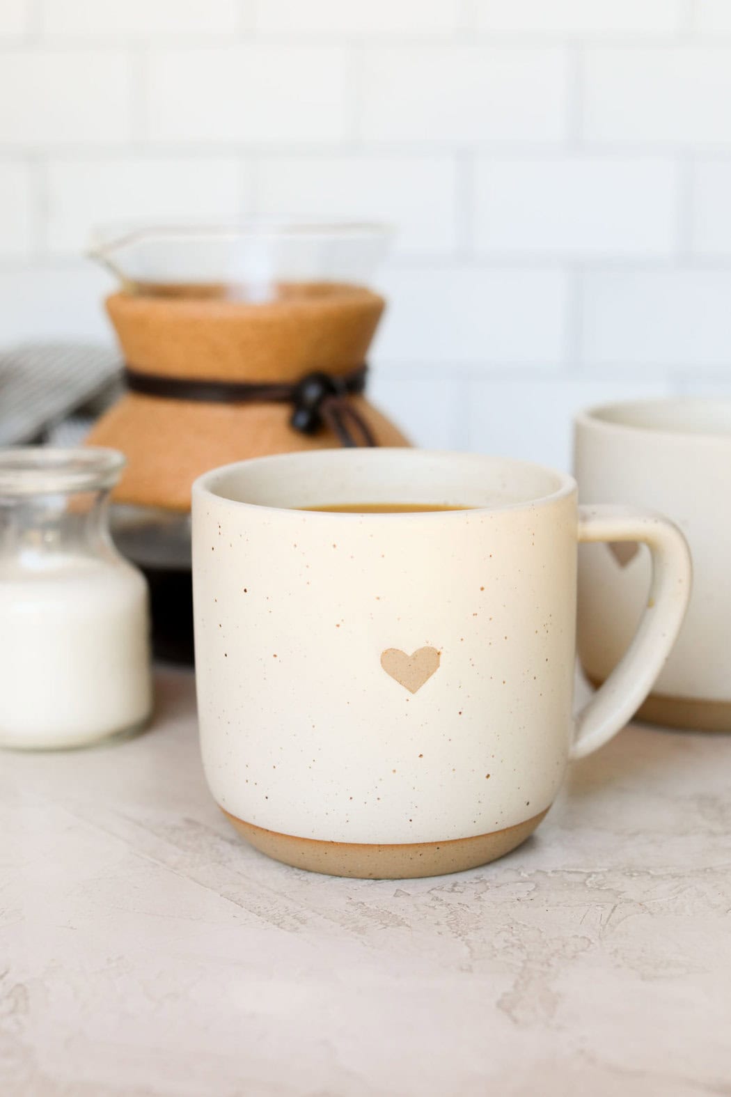 Close up view of a white coffee mug with a heart on the front. 