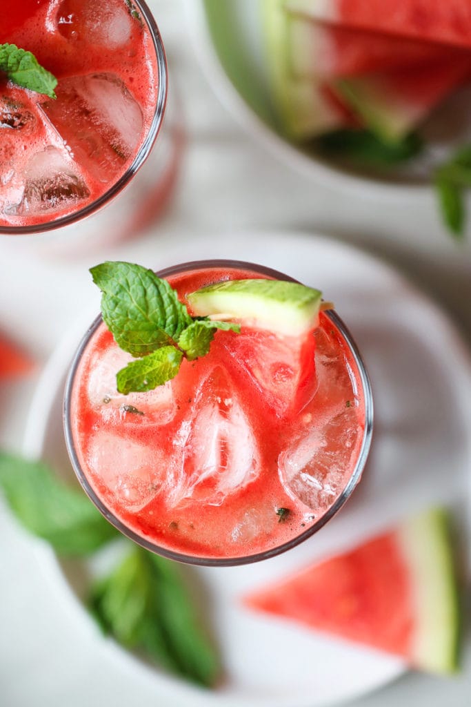Overhead view watermelon mojito in tall glasses garnished with fresh mint sprigs and small watermelon slices.