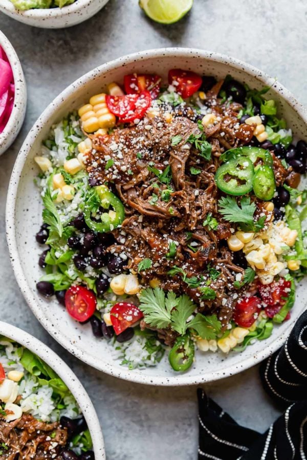 Instant Pot Beef Barbacoa served on a stone plate with all of the toppings - like Chipotle, only better!