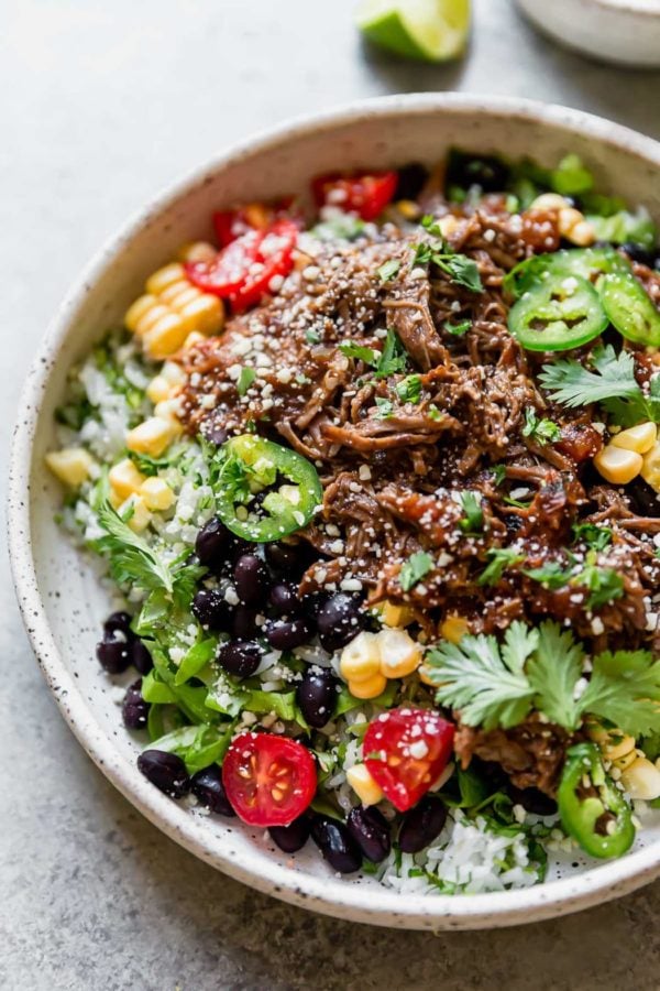 Burrito bowl made with Instant Pot Beef Barbacoa, served on a white plate. 