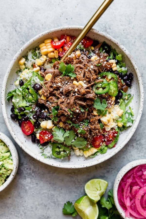 Overhead view of a burrito bowl made with perfectly spiced beef, rice, beans, and all of the toppings. 