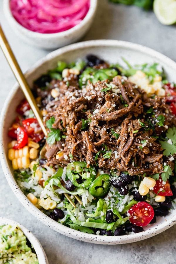 Instant Pot Beef Barbacoa served burrito bowl-style with a gold fork. 