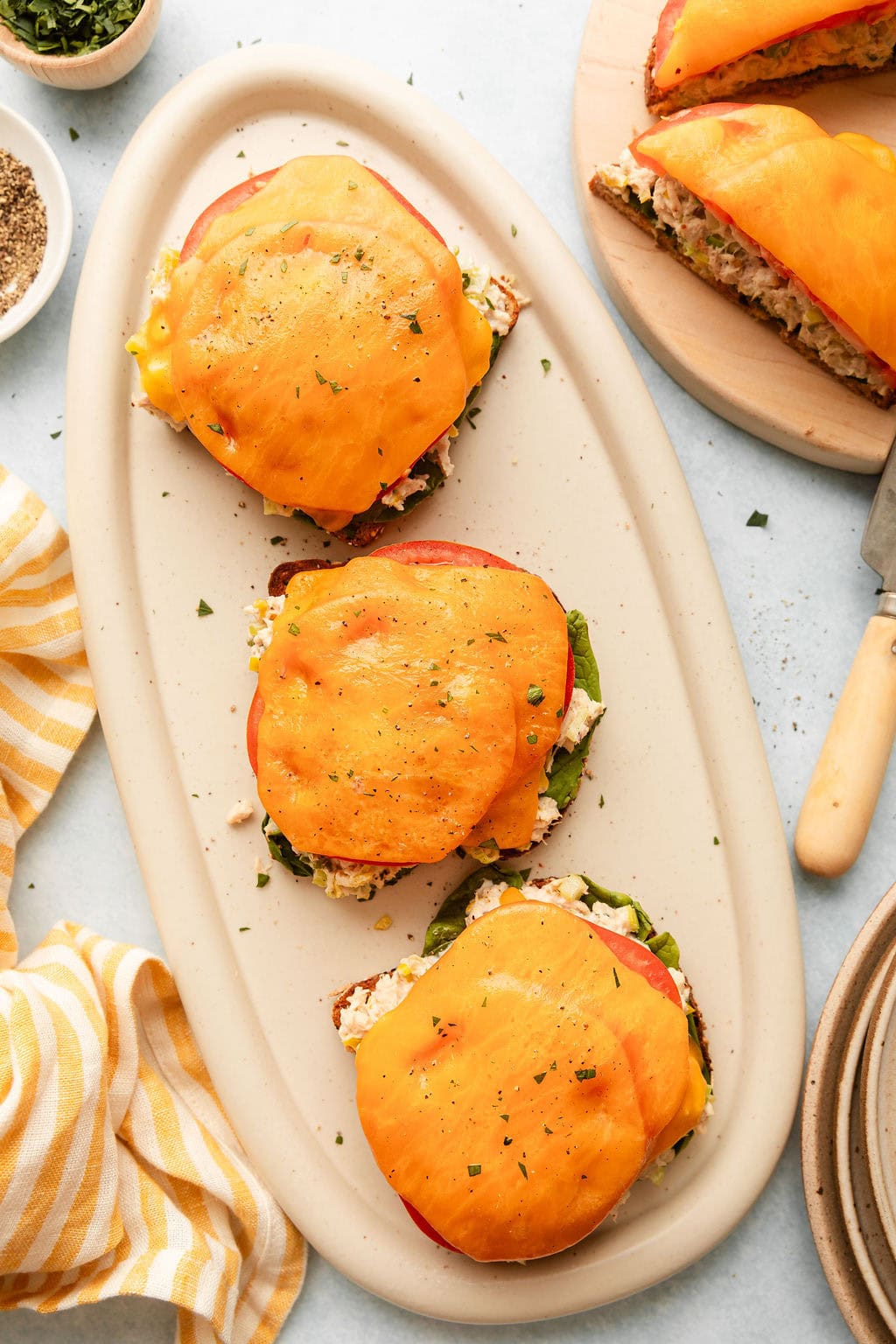 Overhead view of a plate filled with Tuna Melts topped with melted cheddar cheese.