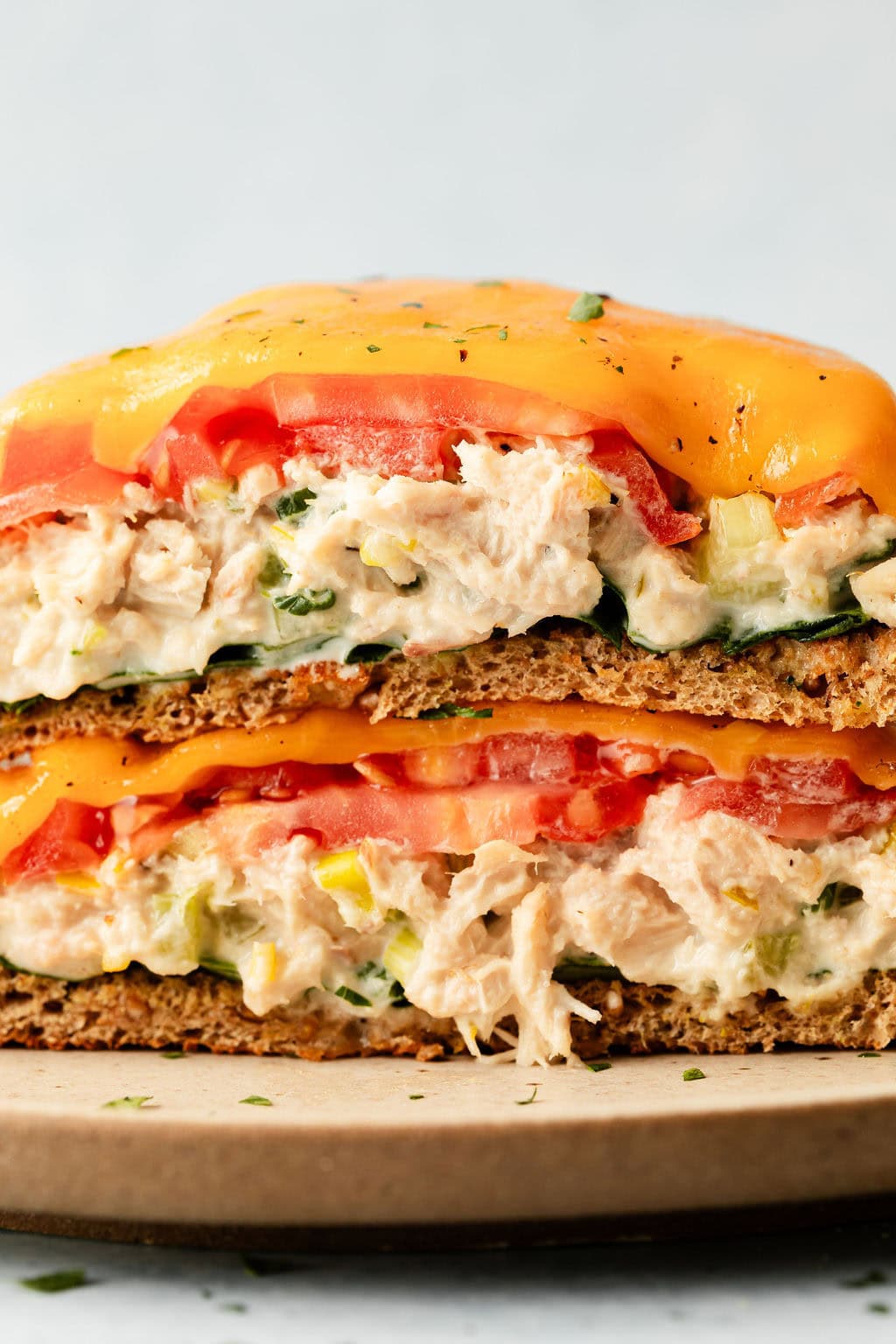 Close up view of two stacked tuna melt open faced sandwiches topped with melted cheese. 
