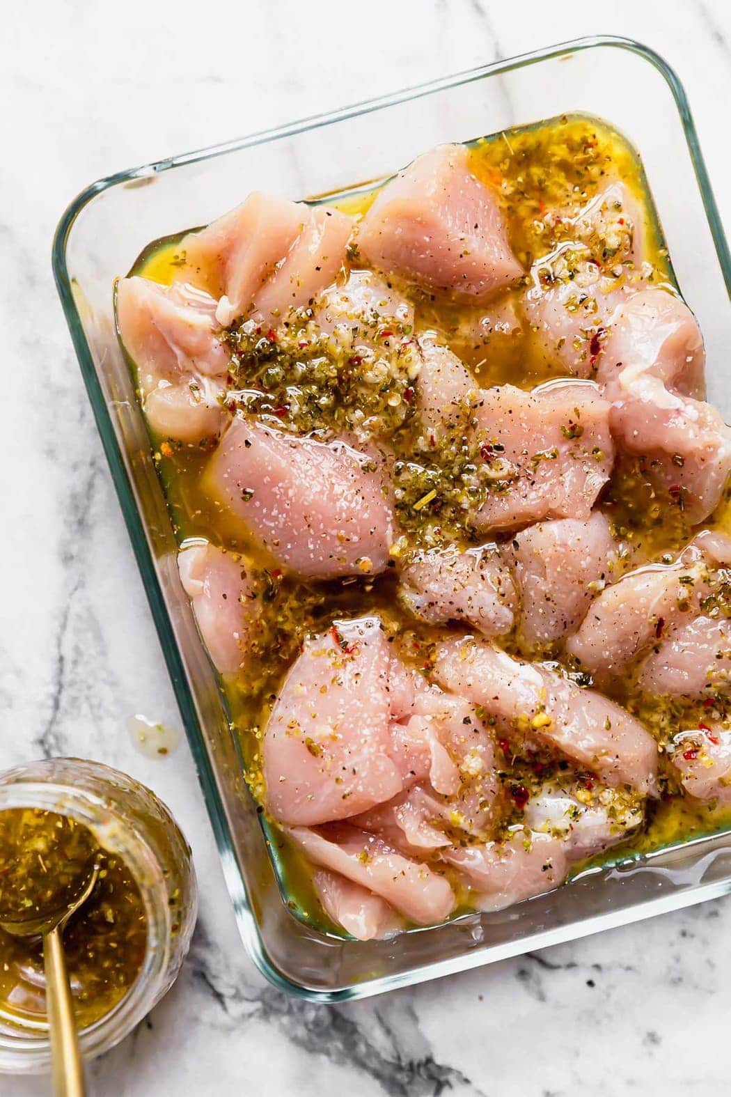 chicken marinading in a glass container