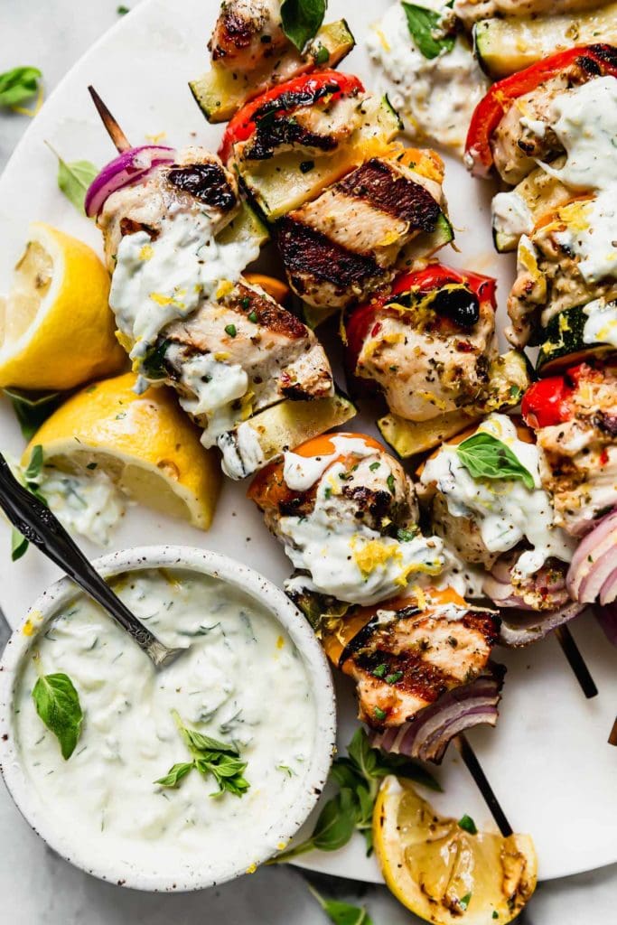 Greek chicken kebobs slathered in homemade Tzatziki sauce plated on a white plate