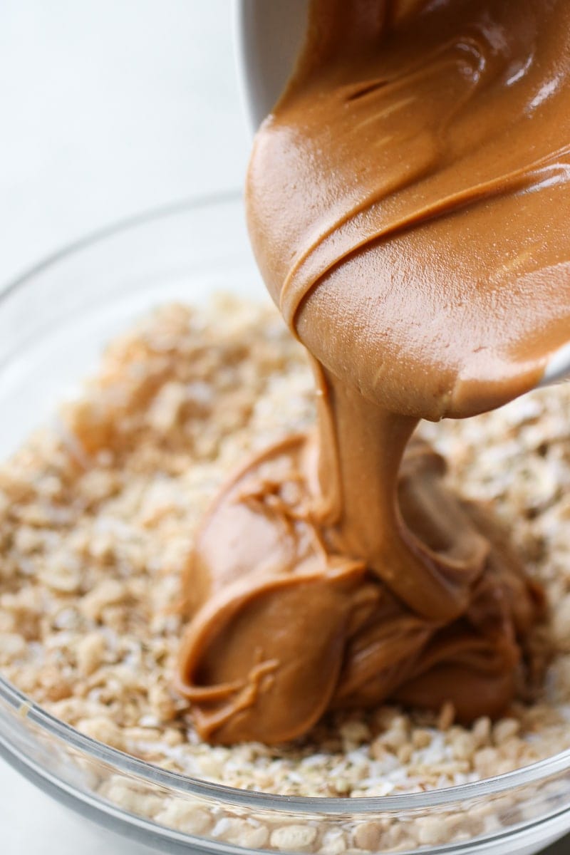 Photo of peanut butter being poured over top of the dry ingredients for the No-Bake Peanut Butter Crunch Bars