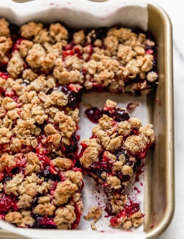 Overhead view dessert bars with fresh berry filling and oat topping, cut into squares in the pan.