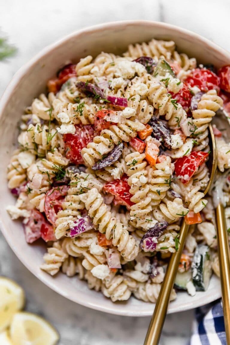 Overhead view of a serving bowl filled with Greek veggie pasta salad topped with feta.