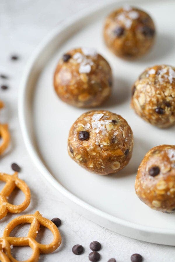 A white platter filled with no-bake healthy peanut butter energy bites and topped with sea salt.