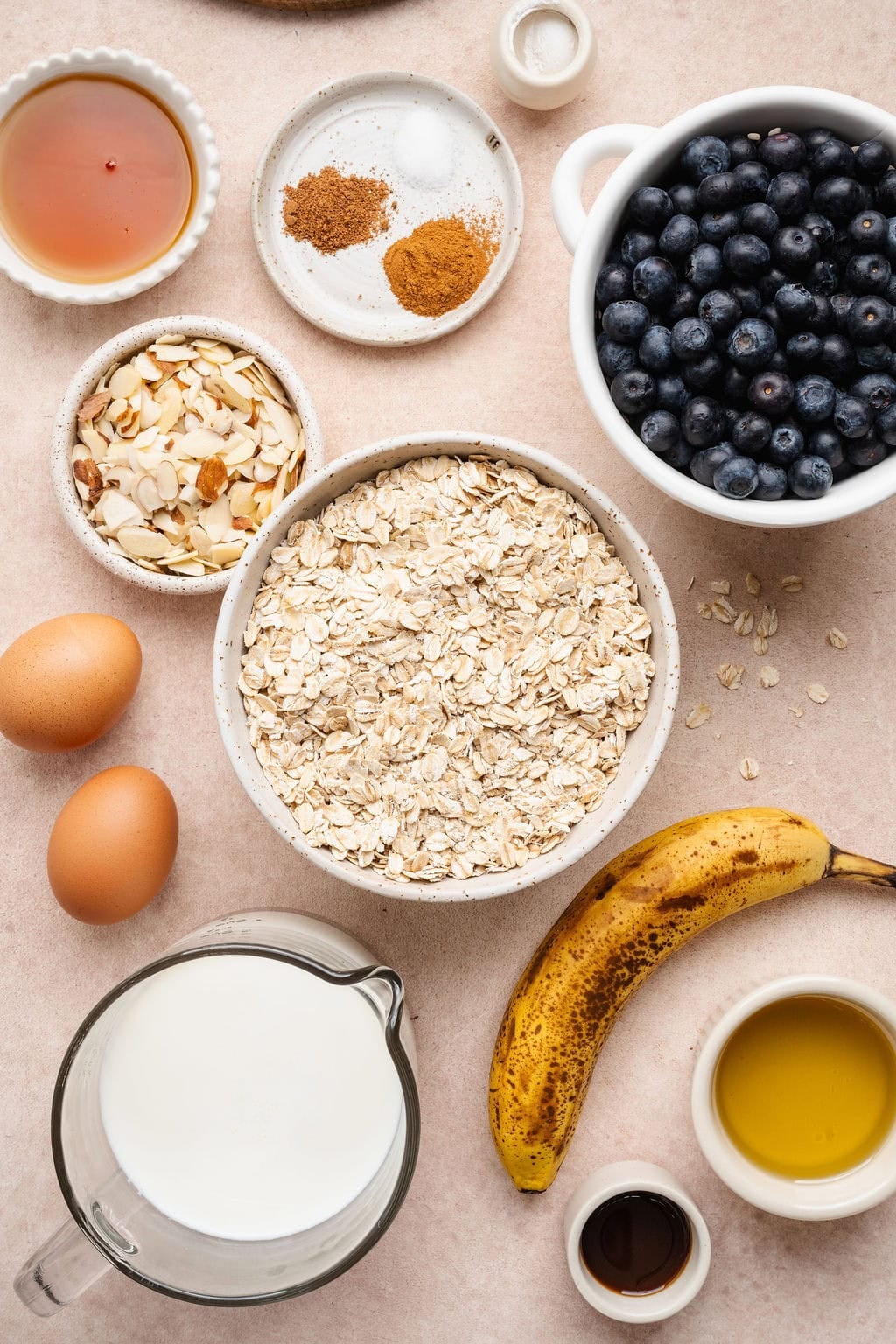 Overhead view of a variety of ingredients for blueberry baked oatmeal in different sized bowls.