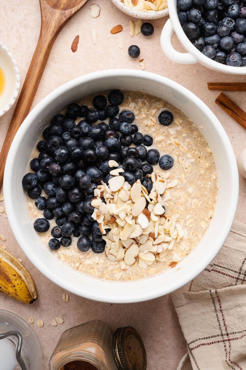 Overhead view of a bowl filled with blueberries and almonds on top of an oatmeal mixture ready for stirring.