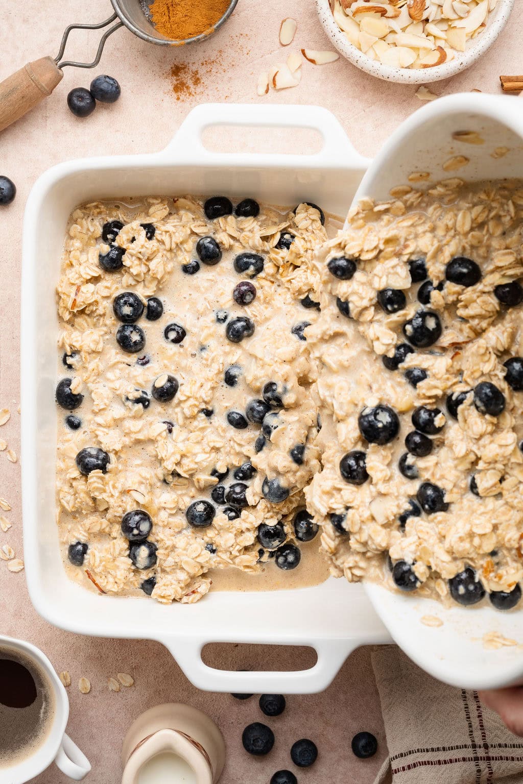 Overhead view of a bowl of blueberry oatmeal mixture pouring into a baking dish.