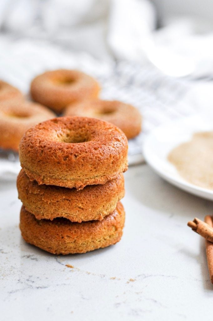 Stack of three pumpkin baked donuts ready to be coated with cinnamon and sugar.
