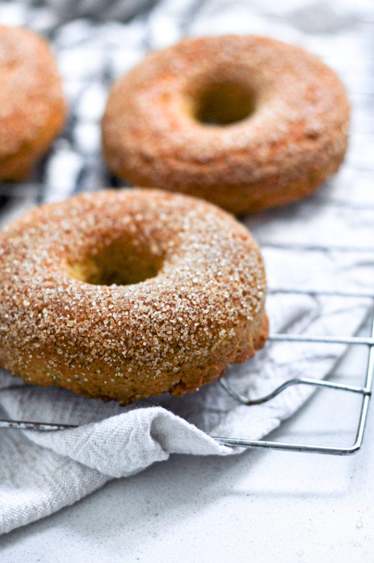 Close up view of a cooling rack filled with baked pumpkin donuts coated in a delicious cinnamon sugar topping. 