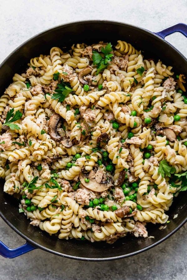 Pasta, peas, mushrooms, onions, and fresh herbs in a cast iron dish before the dairy-free cream sauce is added. 