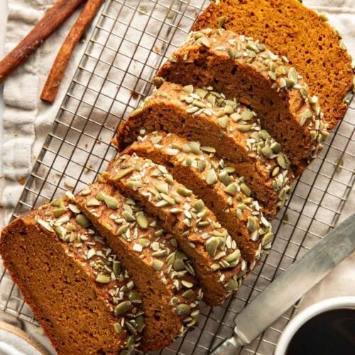 A loaf of pumpkin bread sliced into pieces on a wire rack.