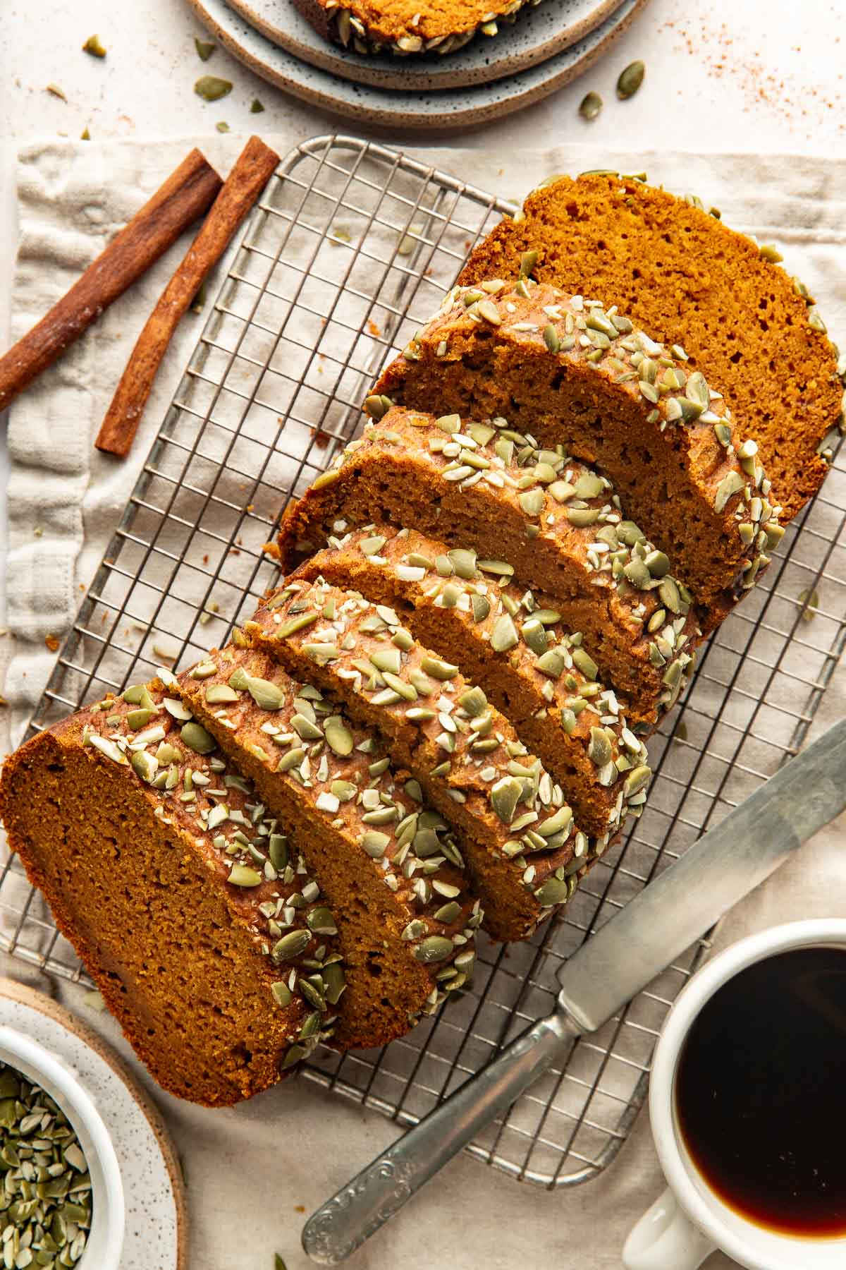 A loaf of pumpkin bread sliced into pieces on a wire rack.