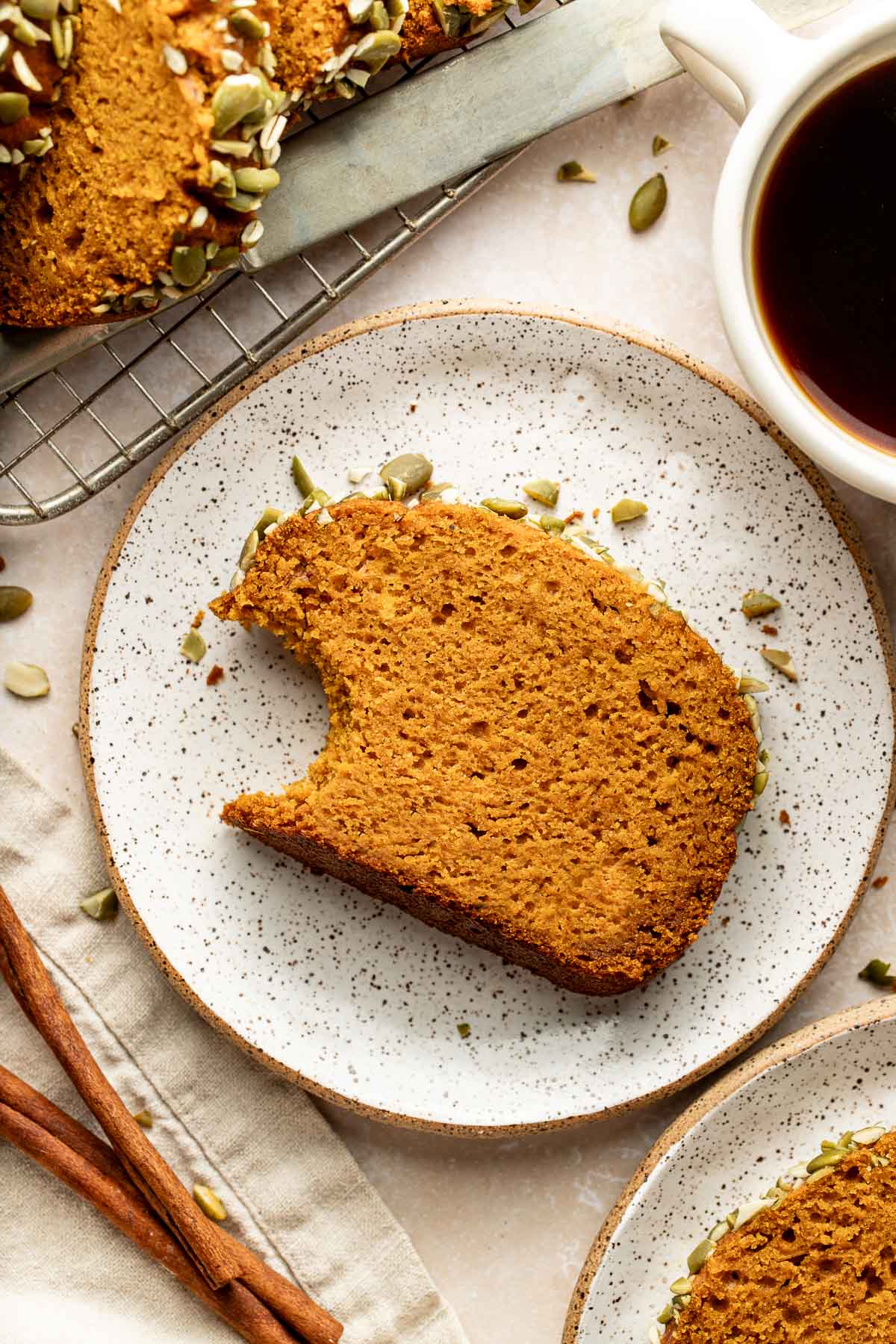 A slice of pumpkin bread on a plate with a bite missing.