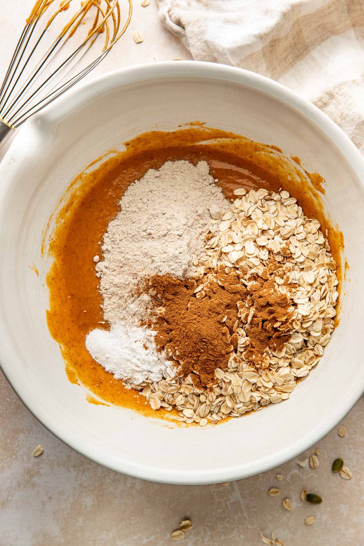 Dry ingredients on top of wet ingredients for pumpkin breakfast cookies in a bowl.