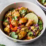 Veggie Chicken Pad Thai in a creamy bowl and topped with cashews and lime wedges.