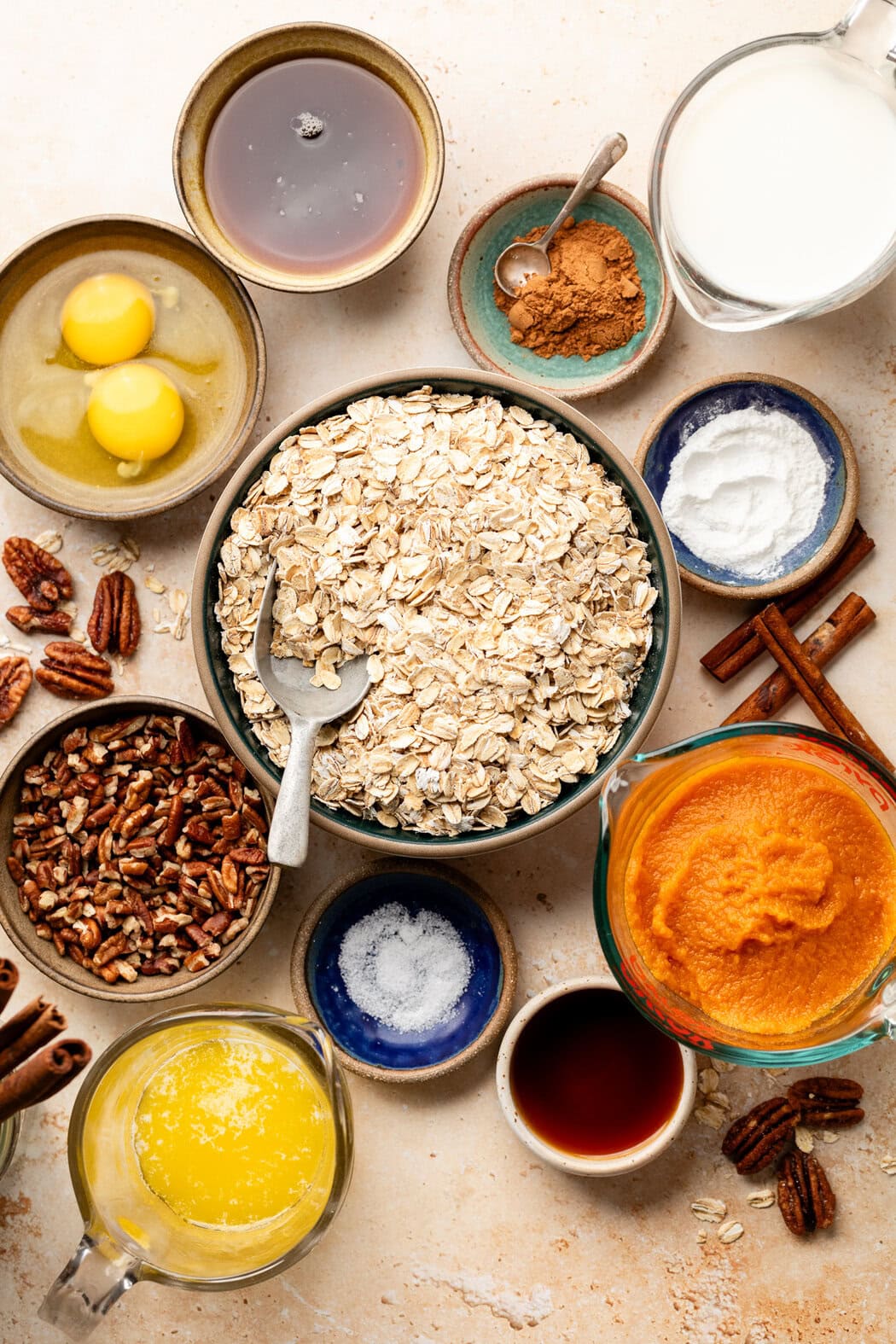 Overhead view of a variety of ingredients for Pumpkin Baked Oatmeal in different sized bowls. 